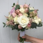 Okrągła kompozycja inspirowana obrazami holenderskich mistrzów. Bukiet w delikatnych kremowych różach, liniowych piwoniach i zgaszonej zieleni liści otulony białą wstążką z perełkami.