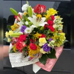 Radosny bukiet pełen barw i zapachów! Róże, goździki, lilie i narcyzy tworzą porywającą kompozycję, otoczoną bibułą z nutowym wzorem. Letnia harmonia kwiatów!