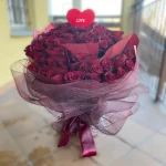 Wspaniały, okrągły bukiet ze 100 czerwonych róż oryginalnie przeplecionych czerwoną bibułą.