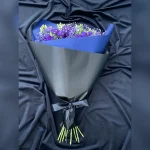 Elegancki bukiet kondolencyjny w niebieskiej tonacji z eustomą, gipsówką, czarną bibułą i dużą kokardą