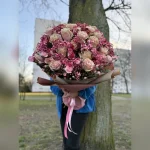 Bukiet w odcieniach różu z gipsówką, goździkami i kremowo-różowymi różami zachwyca elegancją. Subtelna bibuła podkreśla pastelową harmonię tej wyjątkowej kompozycji.